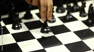 Arrangement of black chess pieces on chess board, with pawn moving.