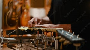 Guitar luthier hands polishing the frets on the fretboard in a workshop