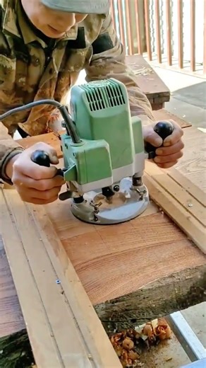 A craftsman operates a large wood router machine on a thick wooden plank precisely