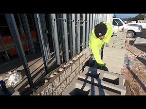 Laying splitface block teaching issac how to spread mortar