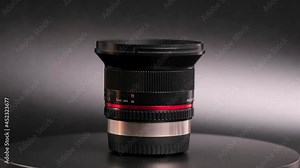 A rotating lens of a professional camera on a gray background