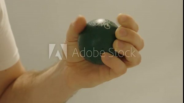 A hand squeezes a green stress ball to calm down and release tension — symbol of relaxation and stress relief.