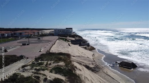 Biscarrosse Plage, France. View descending toward the remains of the beach after winter storm waves eroded the dune, with a beach bar and a fallen bunker visible in the sand.