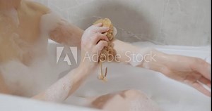 Close up woman blowing foam in slow motion. Young girl playing with bubbles in bathtub at home. Smiling girl having fun with foam in bath. Woman taking bath. Young Woman lying in bathtub. lady wash