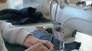 Sewing Machine Needle in Motion. Close-up of sewing machine needle rapidly moves up and down. The tailor sews black fabric on the sewing workshop. The process of sewing fabric