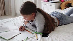 Girl doing her homework on her bed - Free Stock Video