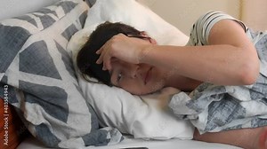 A young woman lies on the bed on a bright day. Woman puts on sleep mask and falls asleep. slow motion Full HD footage