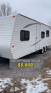 used 24-foot travel trailer listed for $5,800, focusing on which issues are easy fixes and which ones would be deal breakers. From the outside, the trailer shows cosmetic wear such as faded siding and a missing clearance light, but the body panels look straight and the unit sits level. Inside, the flooring near the entry feels solid, which is one of the most important checks on older travel trailers. The living area furniture shows age, but the structure feels intact. The kitchen is dated, with 