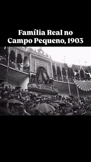 🎟️ O “camarote VIP” mais exclusivo de Lisboa A fotografia mostra o camarote real da Praça de Touros do Campo Pequeno, decorado com pompa e bandeiras, durante a visita de Afonso XIII de Espanha a Portugal. O jovem monarca, então com apenas 17 anos, foi recebido por D. Carlos I e D. Amélia, num dos eventos mais mediáticos da época, símbolo da reaproximação diplomática entre as duas monarquias ibéricas. Na imagem, sob uma chuva ligeira que fez abrir chapéus entre o público, é possível sentir o ent