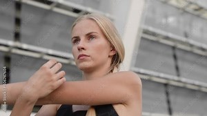 Female sprinter stretching before competition at stadium, marathon runner, sport
