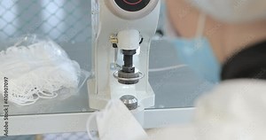 A worker in a protective suit connects a medical FFP3 mask. Hands insert the filter valve into the protective mask. Production of clothing for protection against the virus. Medicine clothing factory. Stock Video