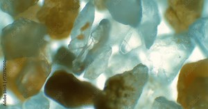 Sand under a miscroscope. Rock under a microscope. Crystals under scope. Microscopic view of sand sample. Cold color.