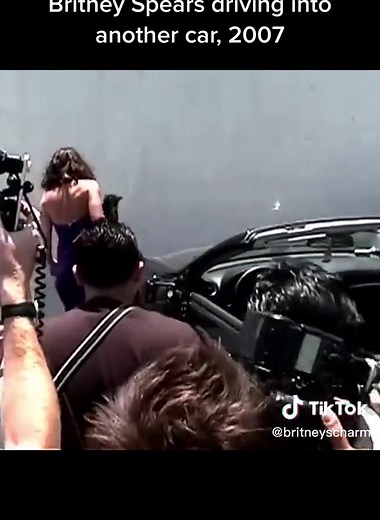 Woman in Purple Dress Surrounded by Group in Parking Lot