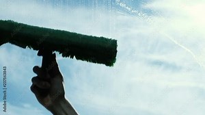 Man washes a dirty window on the balcony, an industrial climber lathers the window outside in slow motion, close-up