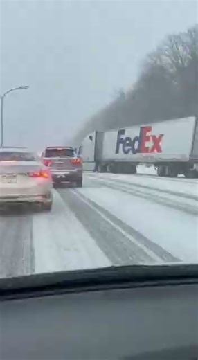 Icy Conditions Trigger FedEx Semi Jackknife in Near-Whiteout Crash Scare Upper Midwest Interstate – A FedEx semi jackknifed during a winter storm after freezing rain turned the interstate into a sheet of ice, according to dash-cam footage from a nearby vehicle. Snow whips across the lens as the truck’s rear trailer slides outward, followed by a violent snap that sends the entire rig sideways. A passing SUV is forced into an emergency maneuver to avoid the swinging trailer. Troopers closed the in