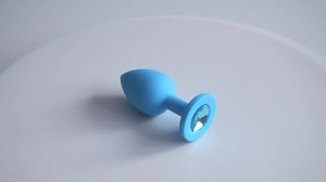 Metal anal plug with blue cristal spinning between on a beautiful female legs in nylon tights.