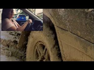 women driving but stuck in mud