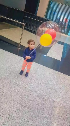 Toddler Enjoys Colorful Balloon in Public Space