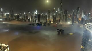 Moonset unfolds as clouds drift past city buildings
