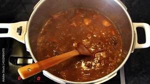 Simmering cuttlefish, pasta in tomato sauce in a pot. Closeup
