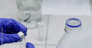 Colleagues insert liquid drop into glass flask in laboratory closeup. Bio materials researching in disease control center. Lab equipment Stock Video