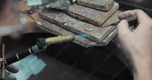 jeweler solders a silver blank with a gas burner in the process of creating a jewelry ring