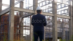 Asian adult foreman stands in front of the construction inspecting a construction project with determination. Engineer inspects construction.