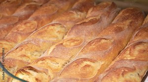 Baked loaves of bread in paper packages on the store shelf, hot crusty baguettes in local Italian bakery shops. Homemade rustic loaves of bread on market counter, traditional flour products in bakery.