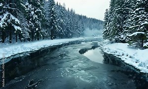 A winding river meanders through a snowy forest, its icy surface reflecting the sky and trees.