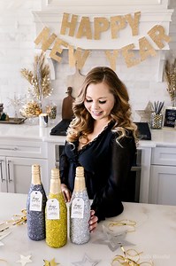 These DIY New Year’s Eve Glittery Glass Bottles are a fun way to make your party drinks extra sparkly at your upcoming New Year’s Eve celebration! I had so much fun glitzing these three sparkling juice bottles. I used to craft with sparkles all the time, and I have a feeling that as our little girl grows, I’ll be creating a lot more glittery projects again. I chose three colorful glitters with a mix of fine and chunky holographic sparkles. And I absolutely love how they turned out! It might be h
