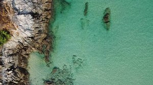 The drone captures a bird's eye view of nature between the cliffs and the sea.