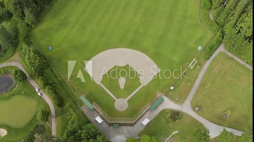 A top down aerial drone view of a green baseball field, baseball diamond, sports field, community park. 4K 24FPS.