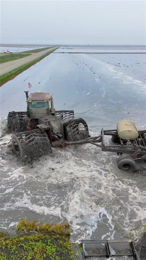 A tractor planting seeds in a waterlogged field.