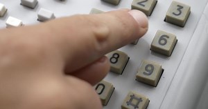 fingers dialing a number on an old landline telephone