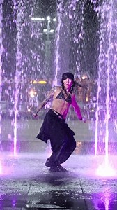 Artist performance. Graceful woman in wet clothes dancing in colorful fountain. Woman dancing outdoors in evening. Vertical video. Slow motion in 4K, UHD