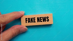 Fake news message writing on wooden block on blue background. Conceptual fake news symbol. Copy space.