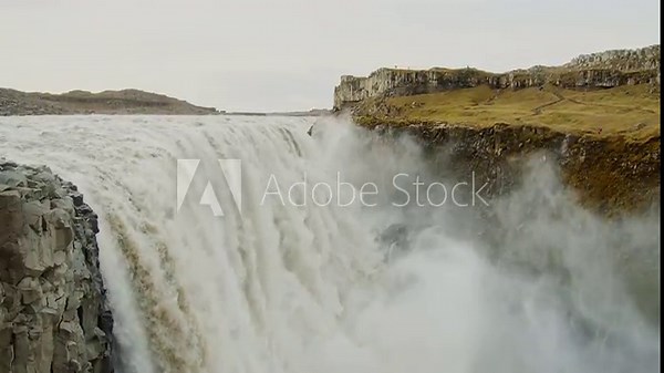 A stunning wide shot of the Dettifoss waterfall in Iceland, Europe's most powerful waterfall. The video captures the immense force of the water as it crashes into the canyon below, creating a thick mi