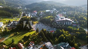 Aerial drone view of Poiana Brasov, Romania. Small town with hotels and parkings located near mountain covered with lush forest