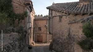 View of the sunset on a narrow street in Calatañazor, a medieval village in Soria. There are old stone houses with traditional architecture