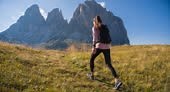Female hiker walks uphill, surrounded by majestic mountain peaks