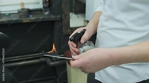 A hairdresser disinfects a straight razor with fire by spraying alcohol to increase the flame. Close-up.