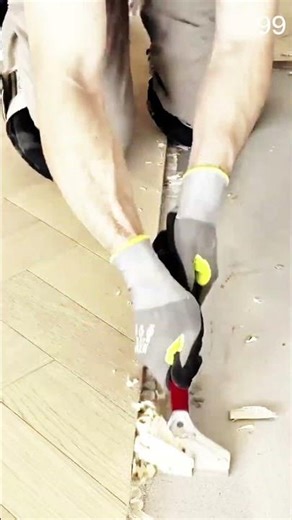 Scraper pries herringbone floor edge, gloves lift boards cleanly as subfloor emerges beneath