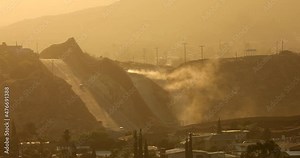 Tecate, Baja California, Mexico - September 14, 2021: Late afternoon sun shines on the USA Mexico border wall as it winds through Tecate.