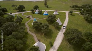 White convertible drive offroad on the background of wigwams