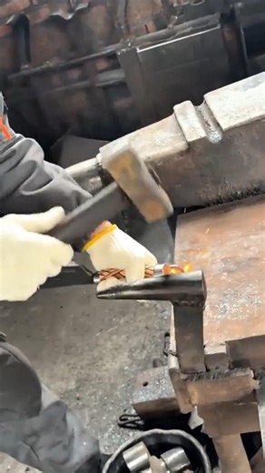 hammering a small hot metal piece on an iron anvil using a manual heavy sledgehammer blacksmith