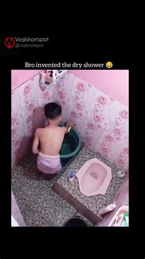 ExploreWorldShots on Instagram: "This clip shows a small bathroom where a man improvises his own unique bathing method in a very confined space. Instead of using a regular shower, he fills a large plastic tub with water and positions it under a wall tap. As the water flows, he repeatedly tilts and spins the tub, letting the water splash over his body. The setup looks awkward but surprisingly effective, turning a simple bucket into a full-body rinse system. The bathroom features patterned tiles,