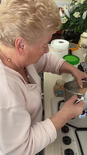 Elderly Woman Cooks Delicious Meal in Cozy Kitchen