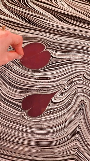 The Soft Asylum by Brittani Locke on Instagram: "Some processes reward patience, not perfection. The art of marbling is one of them. This technique reminds me that color doesn’t need control to be beautiful. Let the water lead and the pattern surprise you. The best patterns happen when you stop forcing symmetry and start working with the flow. This fluid black and white design is about letting go, yet the application of the red hearts is very precisely controlled. The two methods combined offer 
