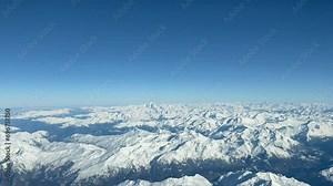 Aerial view of The Alps Mountains shot from a jet cockpit during a real flight in a splendid and bright winter morning with the peaks snowed. A pilot’s perspective at 10000m high.