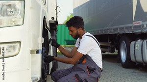 Indian truck driver using socket wrench while changing tire on the road